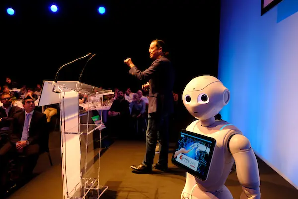 Roberto Menéndez en el escenario con el robot Pepper durante una demostración en una keynote.
