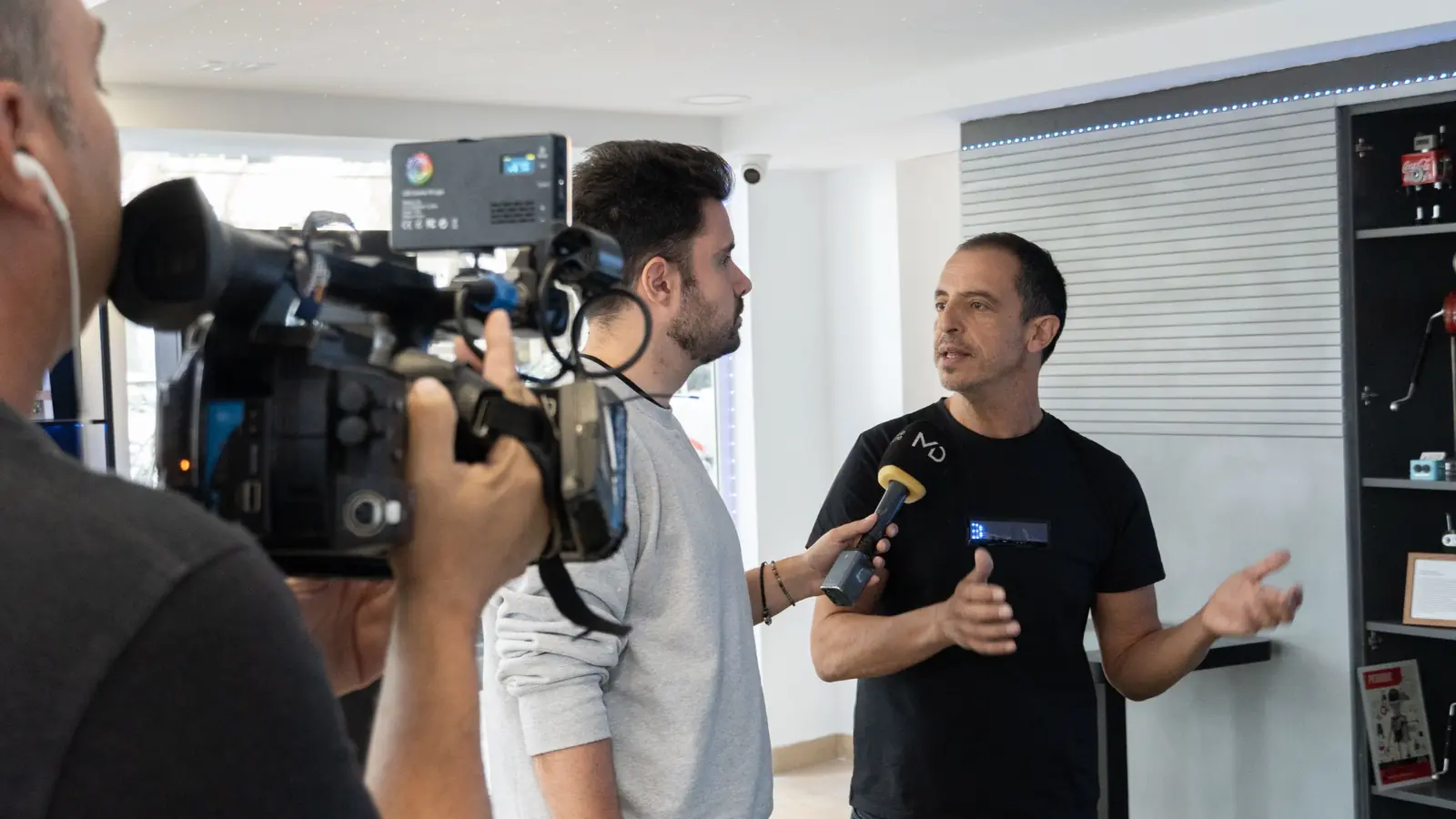 Un cámara y un entrevistador graban a Roberto Menéndez durante una entrevista en medios.